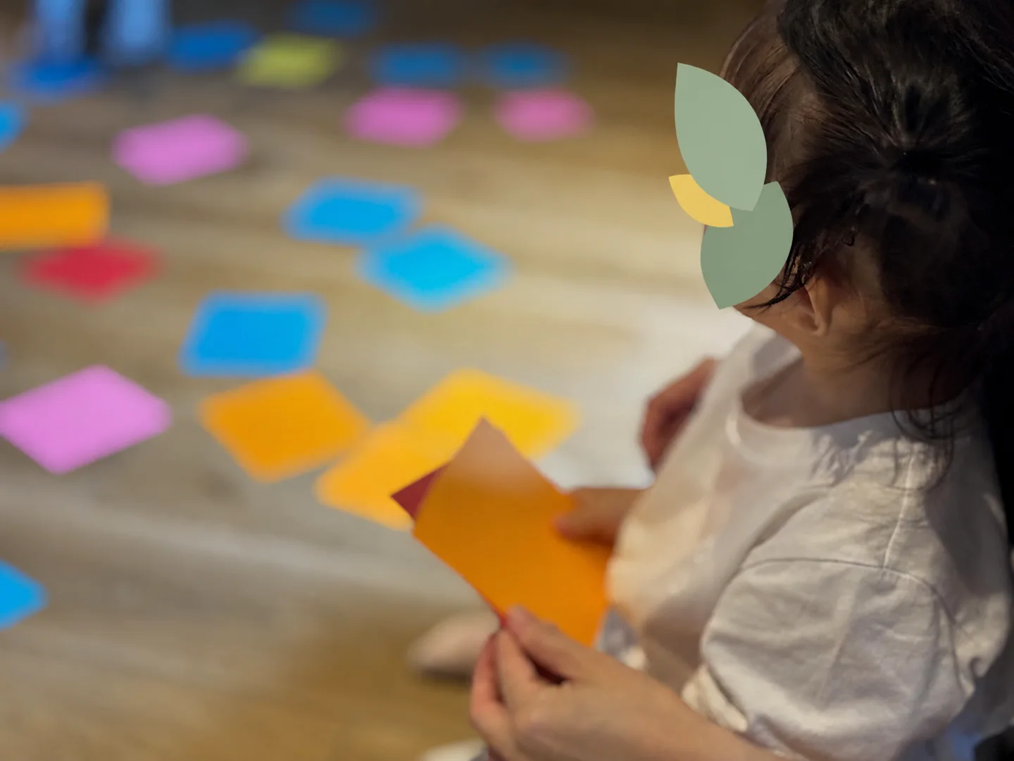 オレンジ色のカードを持って自分のペースで英語遊びに参加する小さな子ども